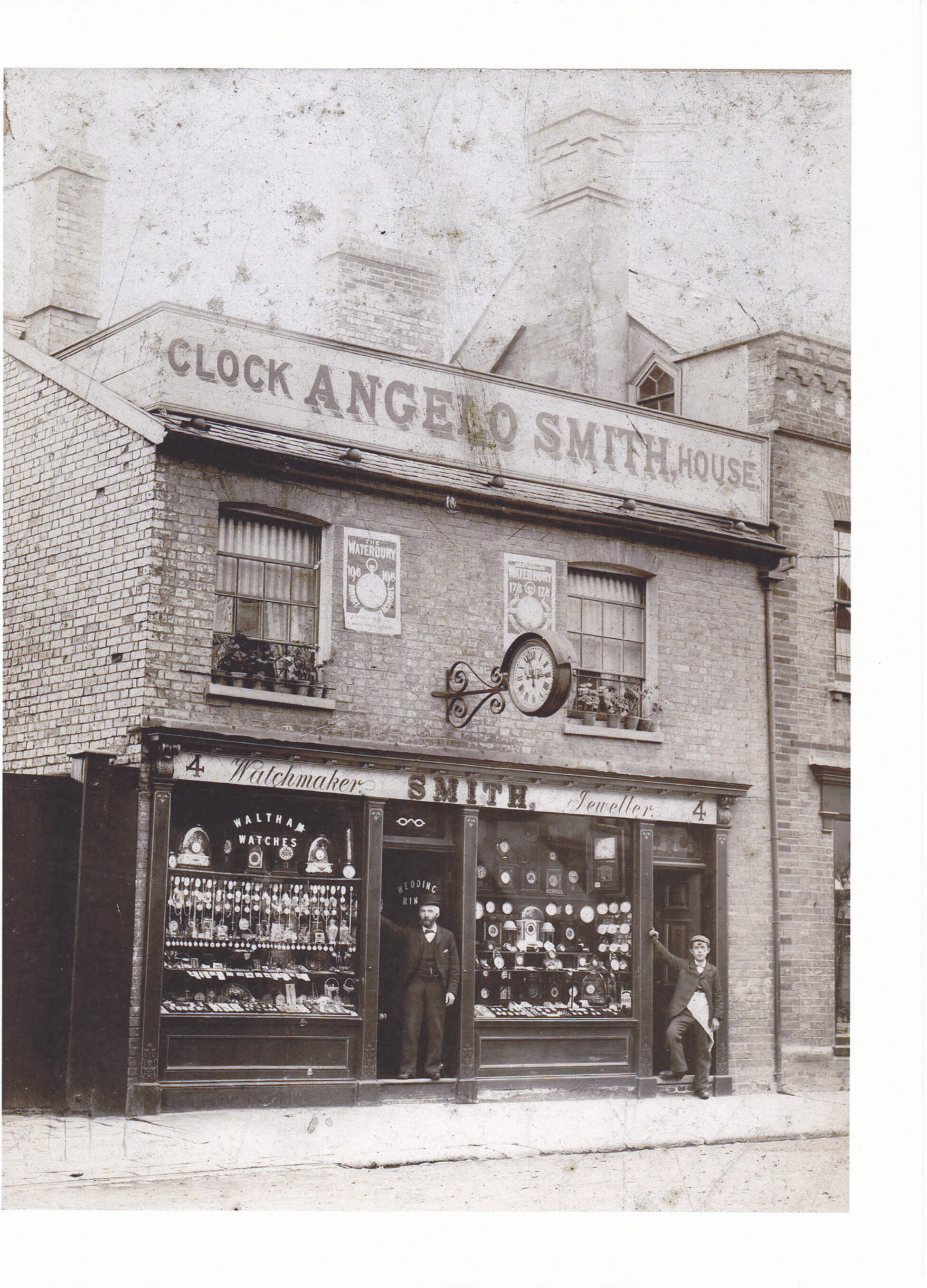 The front of Angelo Smith shop with Angelo standing in the doorway, and his apprentice to the side