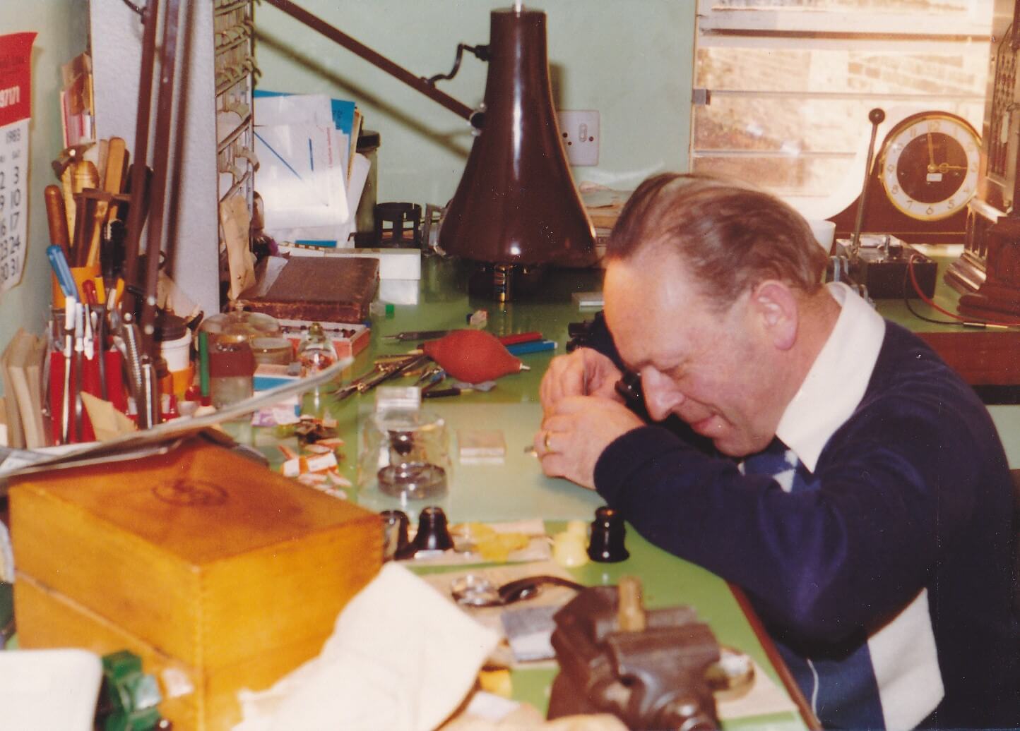 Another workman at his bench, using a small eye loupe to see up close
