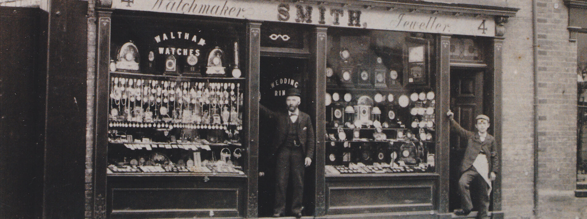 A black and white photo of Angelo Smith standing at the shop door